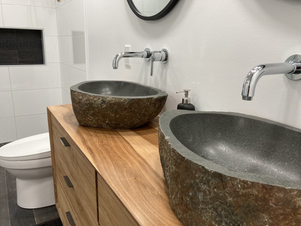 Salle de bain rénovée, lavabo en pierres, robinetterie sur le mur